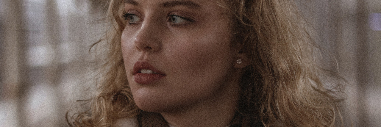 Do I Still Deserve Help for My Mental Health If I Can Work? photo of a blonde woman holding a magazine and looking off to the side in low light