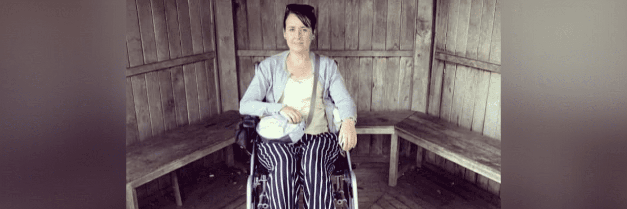 Contributor in her wheelchair in front of wooden paneled wall and benches