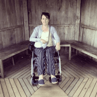 Contributor in her wheelchair in front of wooden paneled wall and benches