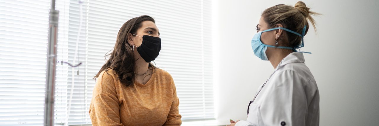 Tips to Help With the First Day of a New Crohn's Disease Diagnosis A white woman with brown hair wearing an orange shirt and burgundy pants sits on an exam table and speaks with a blonde doctor.