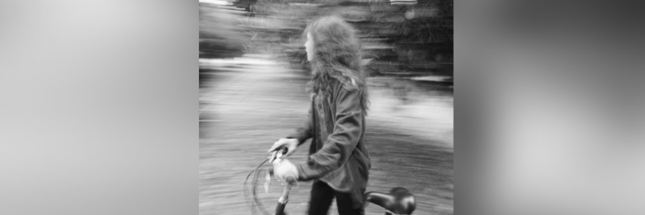 Black and white photo of Zendaya walking with a bike in front of blurred background