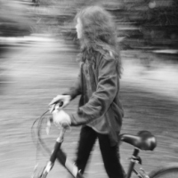 Black and white photo of Zendaya walking with a bike in front of blurred background