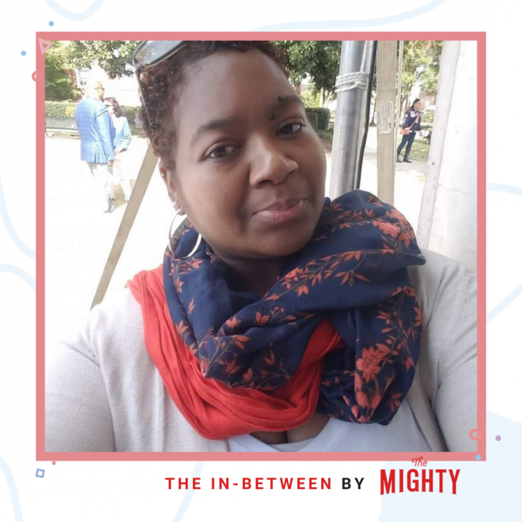 In a light red frame is a woman with a red and blue scarf, hoop earrings, outside in the fresh air. In red text on the bottom reads "The In-Between by The Mighty"