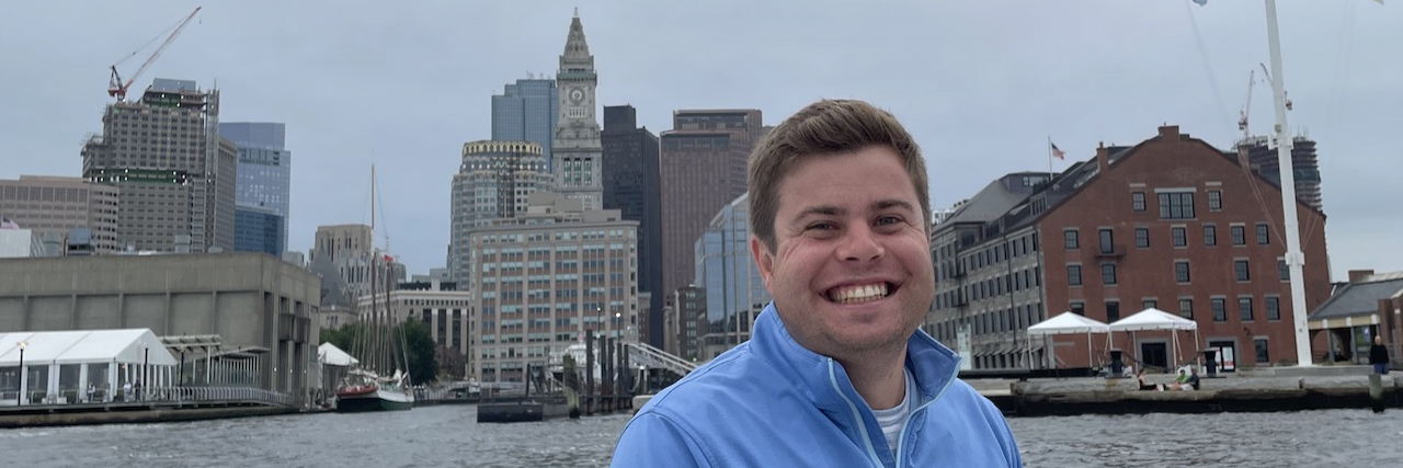 Finding Confidence and Empowerment in Five Years of Sobriety Adam sitting on a boat in a harbor and grinning