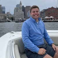 Adam sitting on a boat in a harbor and grinning