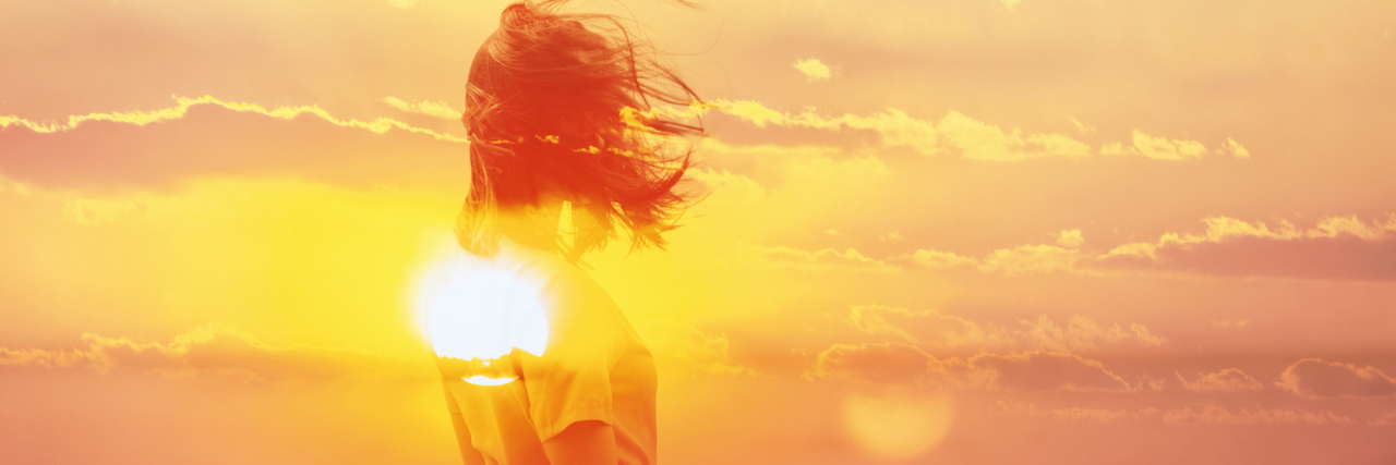 Double exposure of woman and sunset sky.