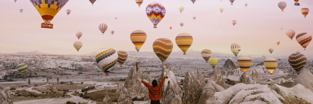 Turning the Rare Disease Stones on My Back Into Balloons Woman with hot air balloons flying around her.