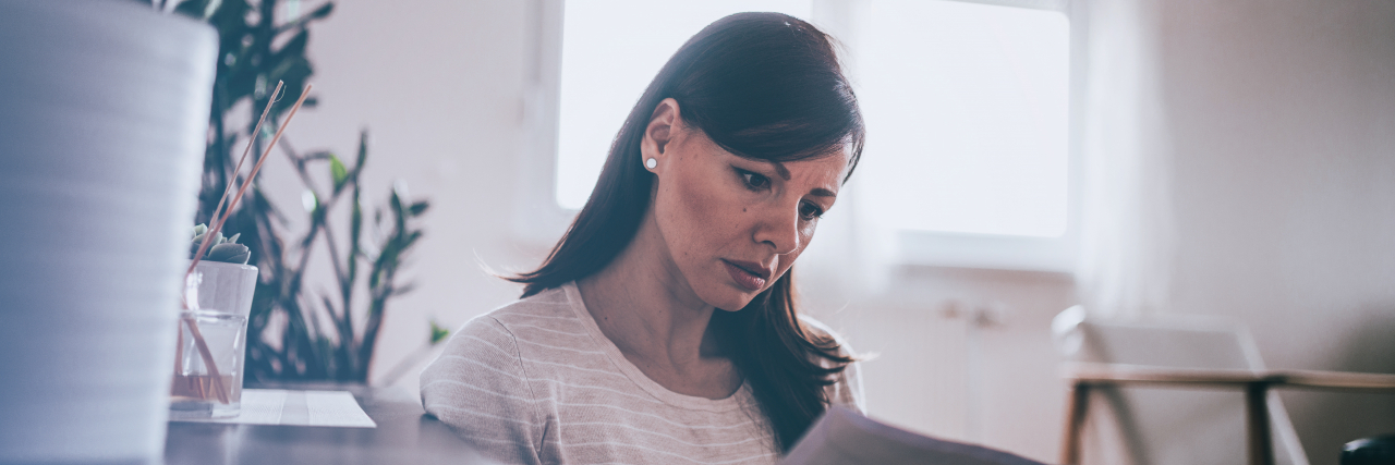 The Moment I Truly Realized Ankylosing Spondylitis Is Lifelong Worried woman reading a letter at home.