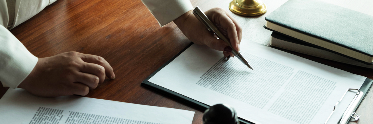 We Need Legislative Change for Both Mental Illness and Addiction Person writing with papers and a gavel on the desk
