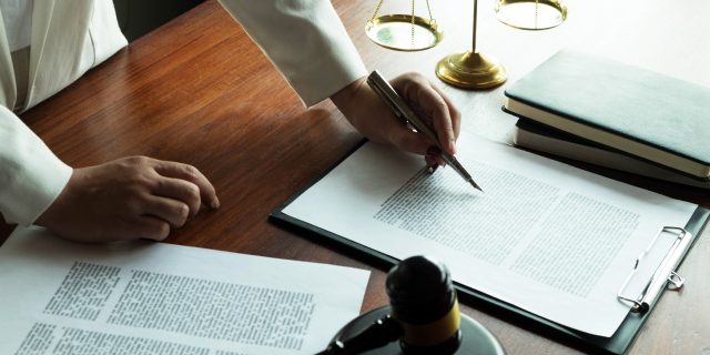 Person writing with papers and a gavel on the desk