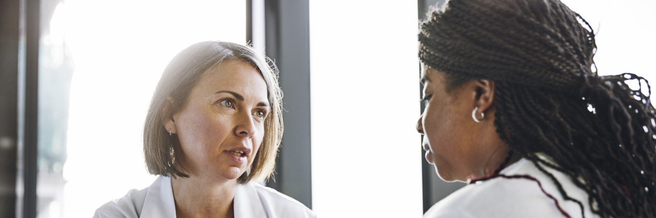 'This Is Not MS' -- When I Was Diagnosed With Neuromyelitis Optica Mature doctor talking to young woman in hospital.