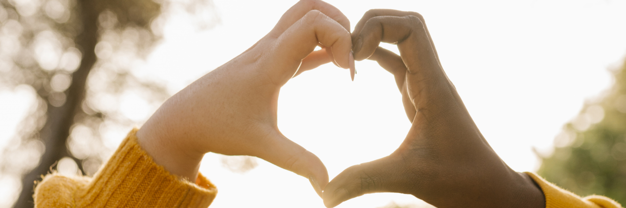 Dating When You've Had a Chronic Illness Since You Were Young Couple making heart shape with hands.