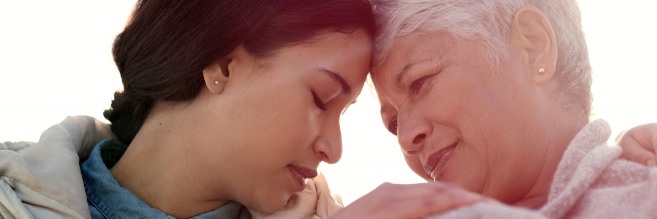 Why Cancer Caregiving Is Hard Even After Treatment Ends An adult daughter and mother. Their heads are pressed against each other and they are holding hands.