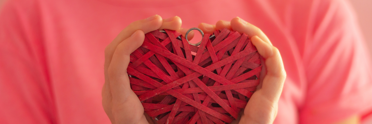 Pink Shirt Day Ignores High Bullying Risk for Kids With Disabilities Girl wearing a pink shirt holding a wicker heart.
