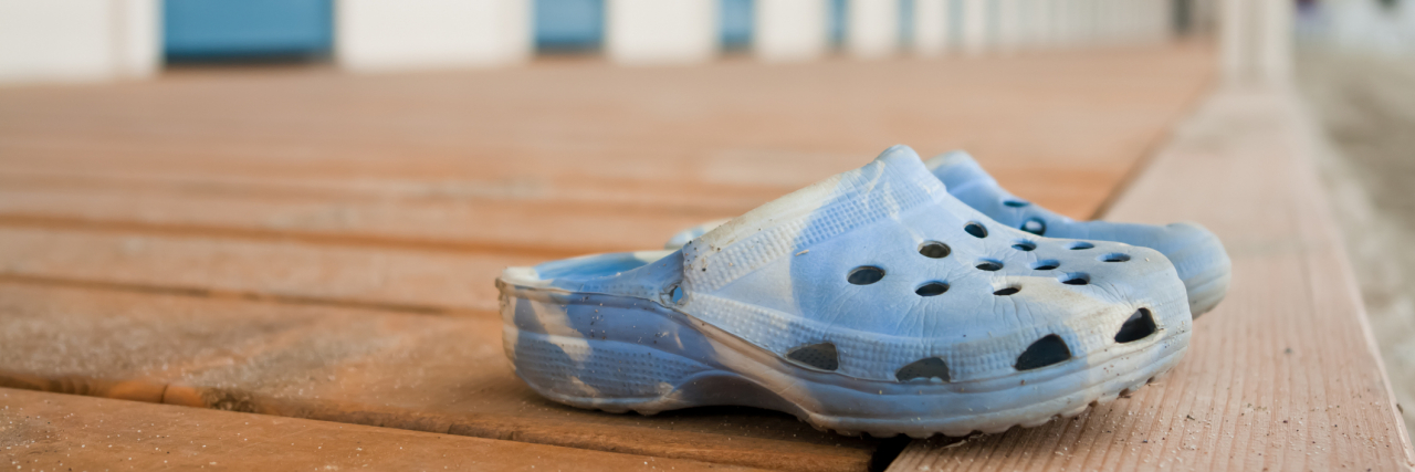Between Psych Hospitals and College, Crocs Have Been My Constant A pair of blue Crocs sitting near the beach