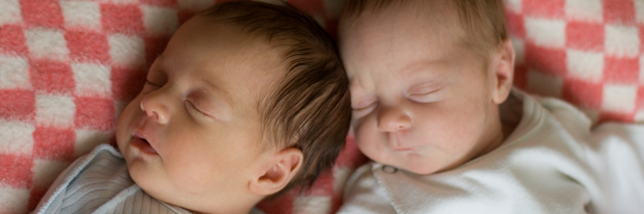 Newborn twins sleeping serenely.