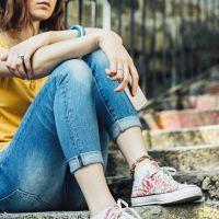 teen girl sitting on steps with cell phone in her hand