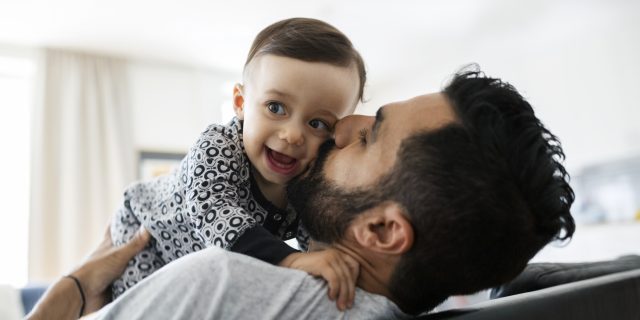 To the Black Dad in the Mirror Looking Back at Me Loving father kissing baby girl while sitting on sofa at home.