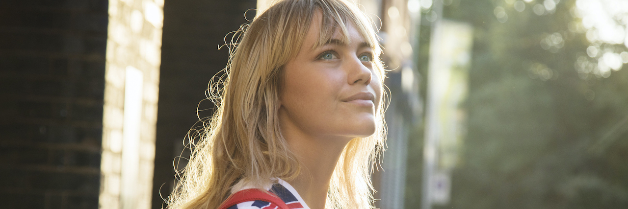 Learning About and Living With Bulimia Woman looks up from phone, standing in city street.