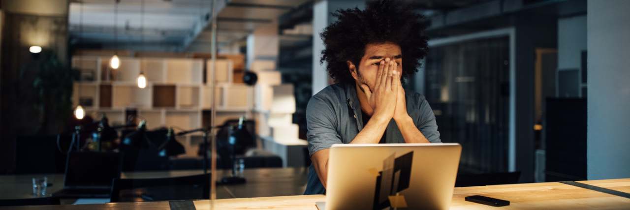 How Workplace Attendance Policies Can Be Ableist Tired businessman working late on laptop while sitting at illuminated desk in office