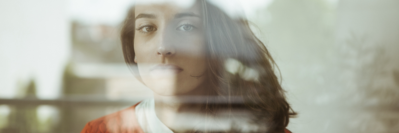 My Husband Took His Life After Hiding Years of Sexual Abuse Portrait of serious young woman behind glass panel