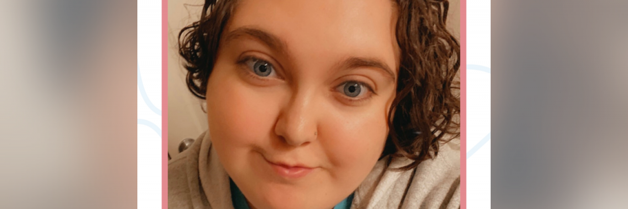 Leukemia Survivor Reflects on Their Cancer Journey In a light red frame is a person with blue eyes and brown curly hair. In red writing below is "The In-Between by The Mighty"