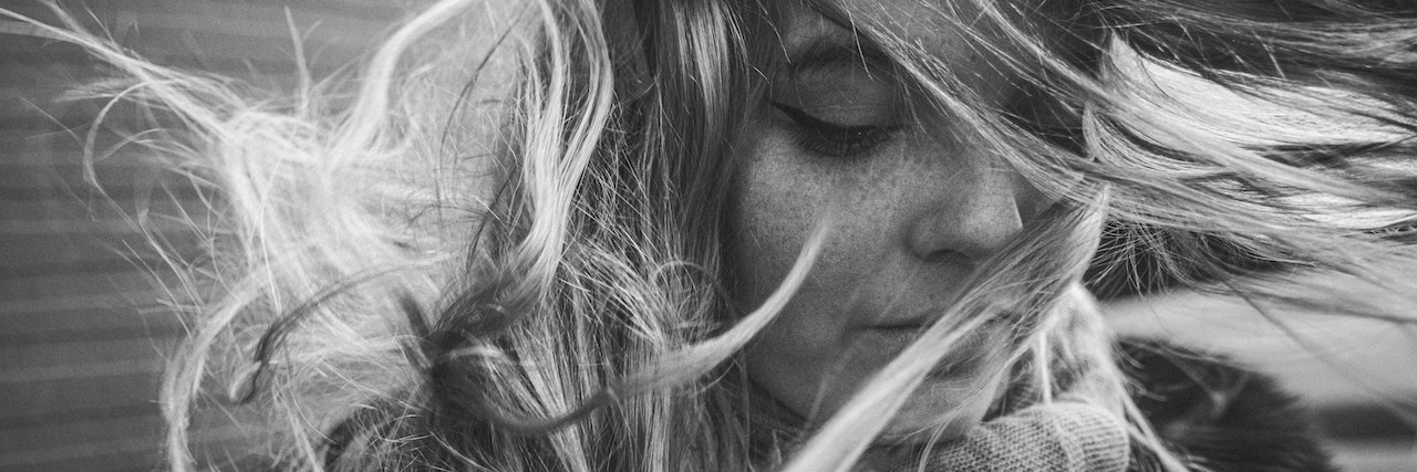 Why People Expressing Pity Makes It Hard to Talk About Suicide Loss A black and white photo of a woman with her hair blowing in her face