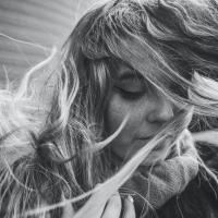 A black and white photo of a woman with her hair blowing in her face