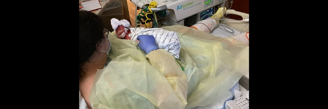 COVID-19 Ruined My Last Birth Experience A mother is lying in a hospital bed holding her newborn baby.