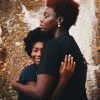 photo of two Black women embracing in front of a wall