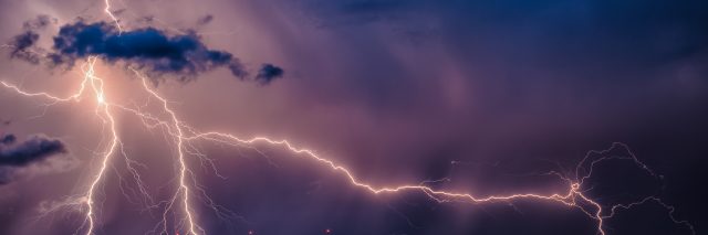 A lightning bolt pierces a night sky.