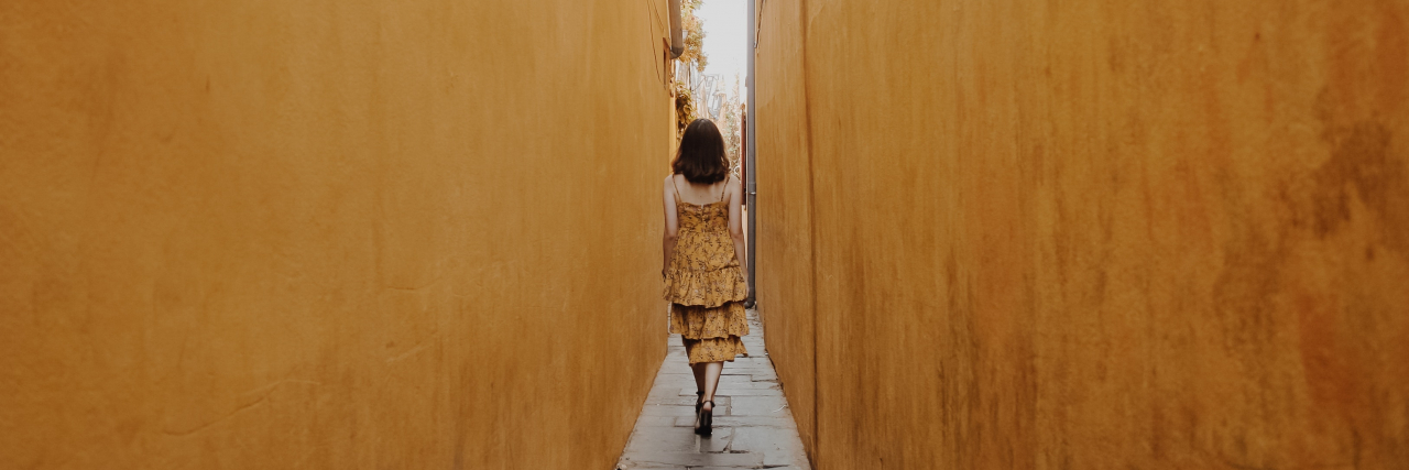 Woman walking down a narrow alley.