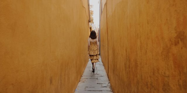 Woman walking down a narrow alley.
