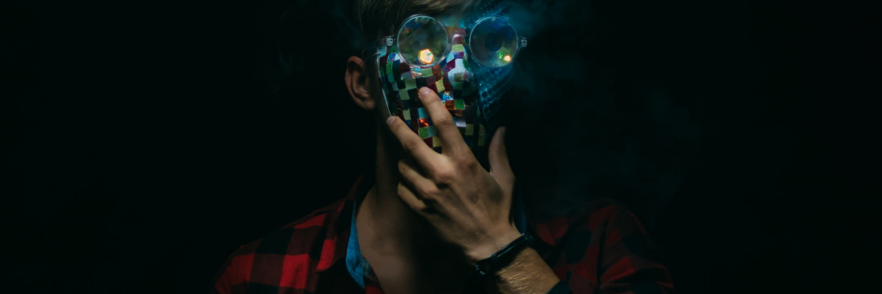 photo of a man with his hand raised to his chin, a digital mask covering his face