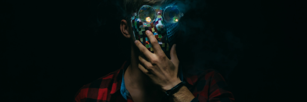 Trauma Nightmares: When I Kick and Punch My Partner In My Sleep photo of a man with his hand raised to his chin, a digital mask covering his face