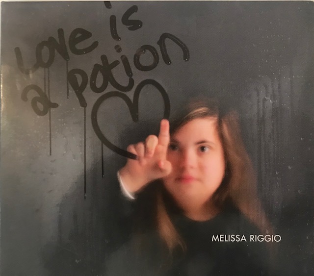 Melissa Riggio writing Love is a Potion on a window.