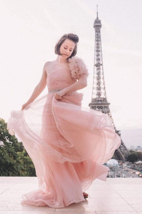 Olivia modeling a pink dress in front of the Eiffel Tower.