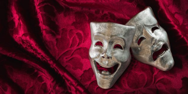 Theater masks, drama and comedy on a red curtain.