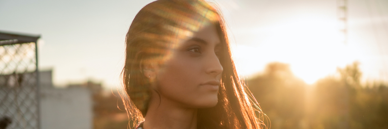 When You Have a Lifelong Struggle With PTSD and Depression Woman of color on rooftop at sunset
