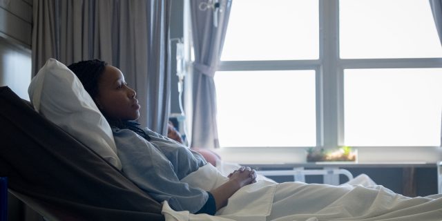 Black woman lying in hospital bed.