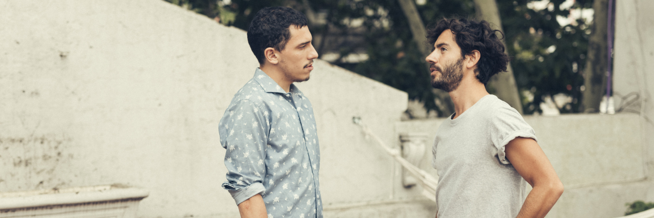 Two men standing outside facing each other talking seriously