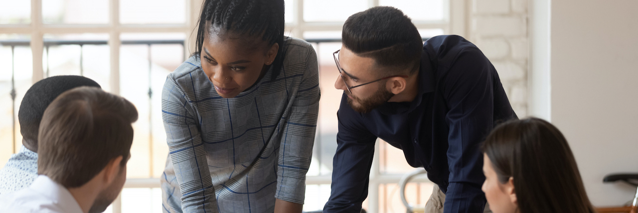 How Systemic Racism Damages Marginalized Communities' Mental Health Black woman working with diverse group of people around conference table