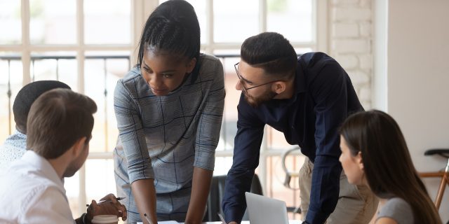 How Systemic Racism Impacts the Mental Health of Marginalized Communities  Black woman working with diverse group of people around conference table