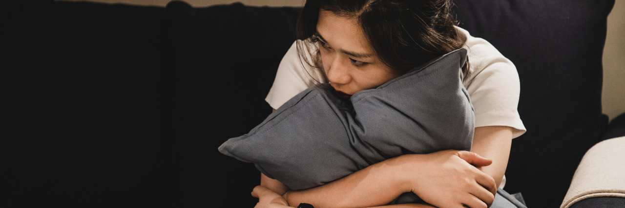 Learning to Control My Anger as an Autistic Woman Sad woman holding a pillow on the sofa.