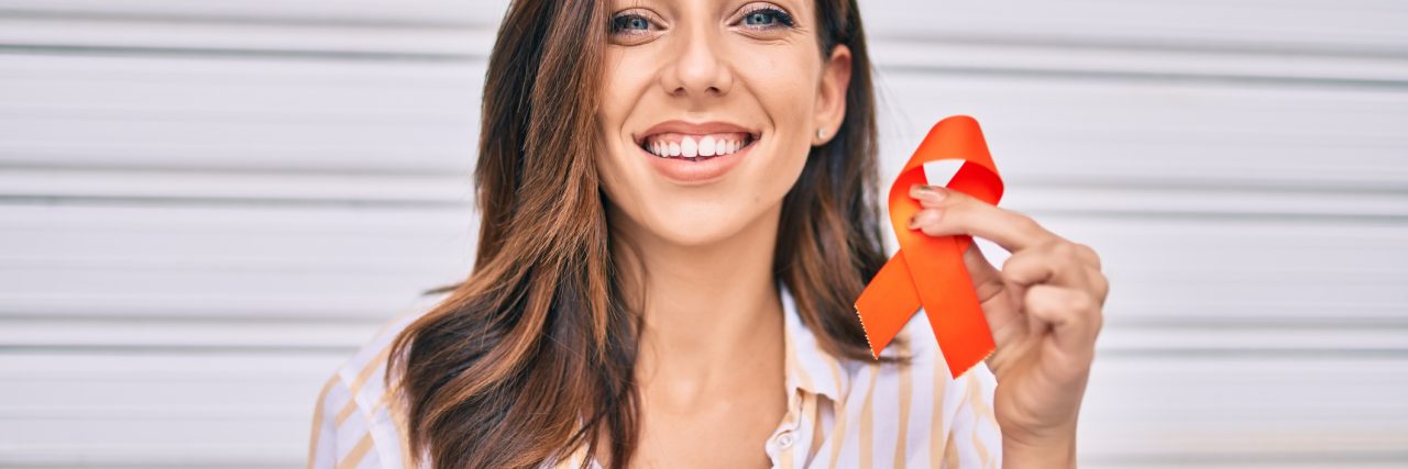Mental Illness Allowed Me to Find My Gift -- My Messy Beautiful Young hispanic woman smiling happy holding awareness orange ribbon standing at the city.