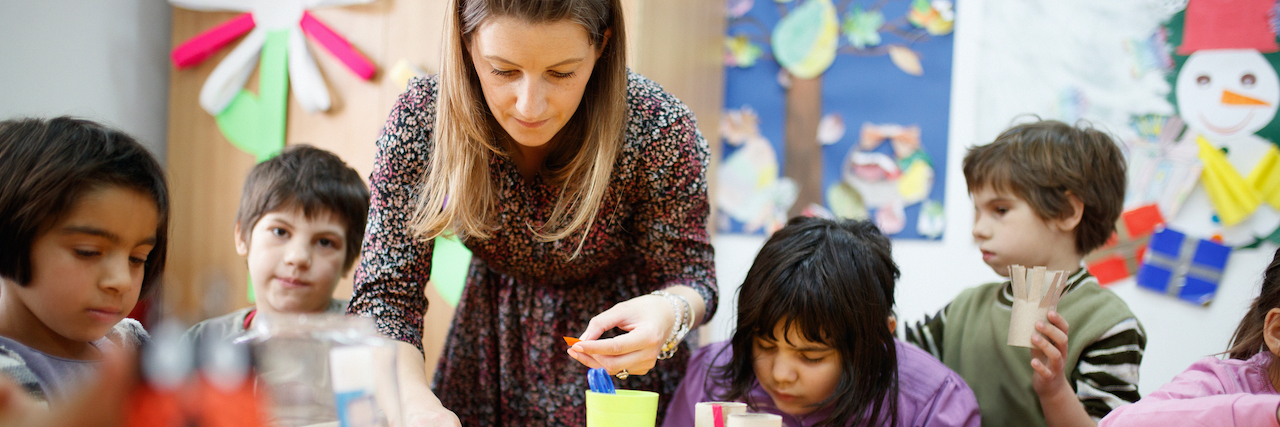 What I Have Learned About the Heart of Teaching  Special education teacher standing by desk in art class and assisting diverse group of elementary students