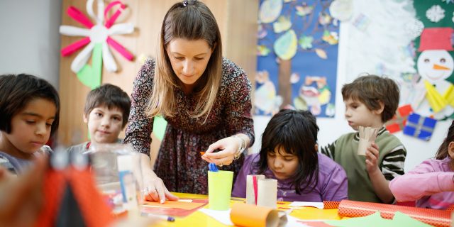 What I Have Learned About the Heart of Teaching  Special education teacher standing by desk in art class and assisting diverse group of elementary students