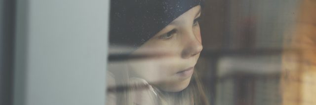 Young girl wearing black cap and looking out window