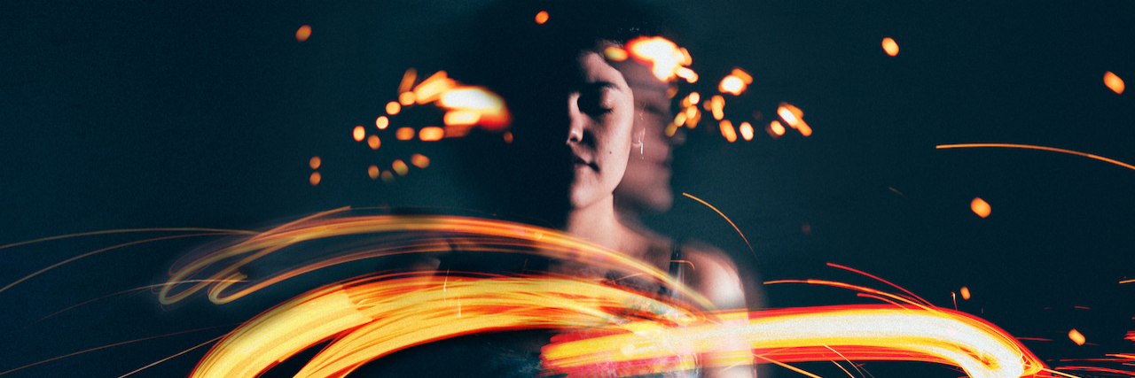 Woman with eyes closed, with light from sparklers in front of her