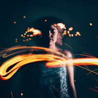 Woman with eyes closed, with light from sparklers in front of her